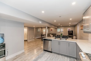 A spacious kitchen with grey cabinets, a dishwasher, and a water dispenser. - Cozy 1-bedroom bungalow in tranquil Barrie with Pool! (Barrie)