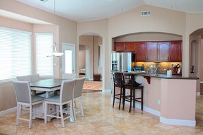 A spacious kitchen with a dining area, featuring a central island, wooden cabinets, and a built-in oven. - Madrone Manor, A Beautiful Spacious Getaway (Elverta)