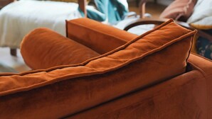 Ein Wohnzimmer mit einer Couch, Sesseln, einem Schrank und einer Pflanze.