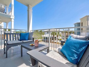 Ein Balkon mit einer Couch, einem Tisch und einem Getränk.