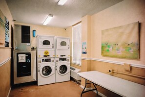 A laundry room with stacked washers and dryers, a small heater, and a painting on the wall. - Ocean View Studio • Pool Sleeps 4 (Daytona Beach)