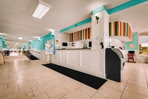 A hotel lobby with a reception desk, a coffee machine, and a seating area with chairs. - Ocean View Studio • Pool Sleeps 4 (Daytona Beach)