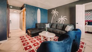 A living room with a sofa, a coffee table, a blue armchair, and a patterned rug.
