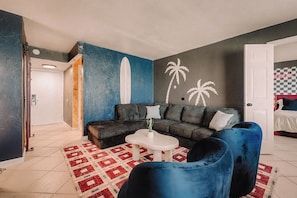 A living room with a sofa, a coffee table, a blue armchair, and a patterned rug.