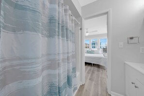 Ein Hotelzimmer mit einem Bett, einem Badezimmer mit Duschvorhang und Blick nach draußen.