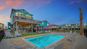 A pool area with lounge chairs and a building with a balcony. - Twin Palms Beach House - Entire Duplex-Private Pool-Steps to the Beach-Sleeps 16 (Gulf Shores)