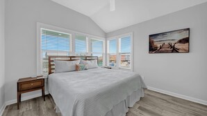 A bedroom with a large bed, a nightstand, a ceiling fan, and a beach-themed painting on the wall. - Twin Palms Beach House - Entire Duplex-Private Pool-Steps to the Beach-Sleeps 16 (Gulf Shores)