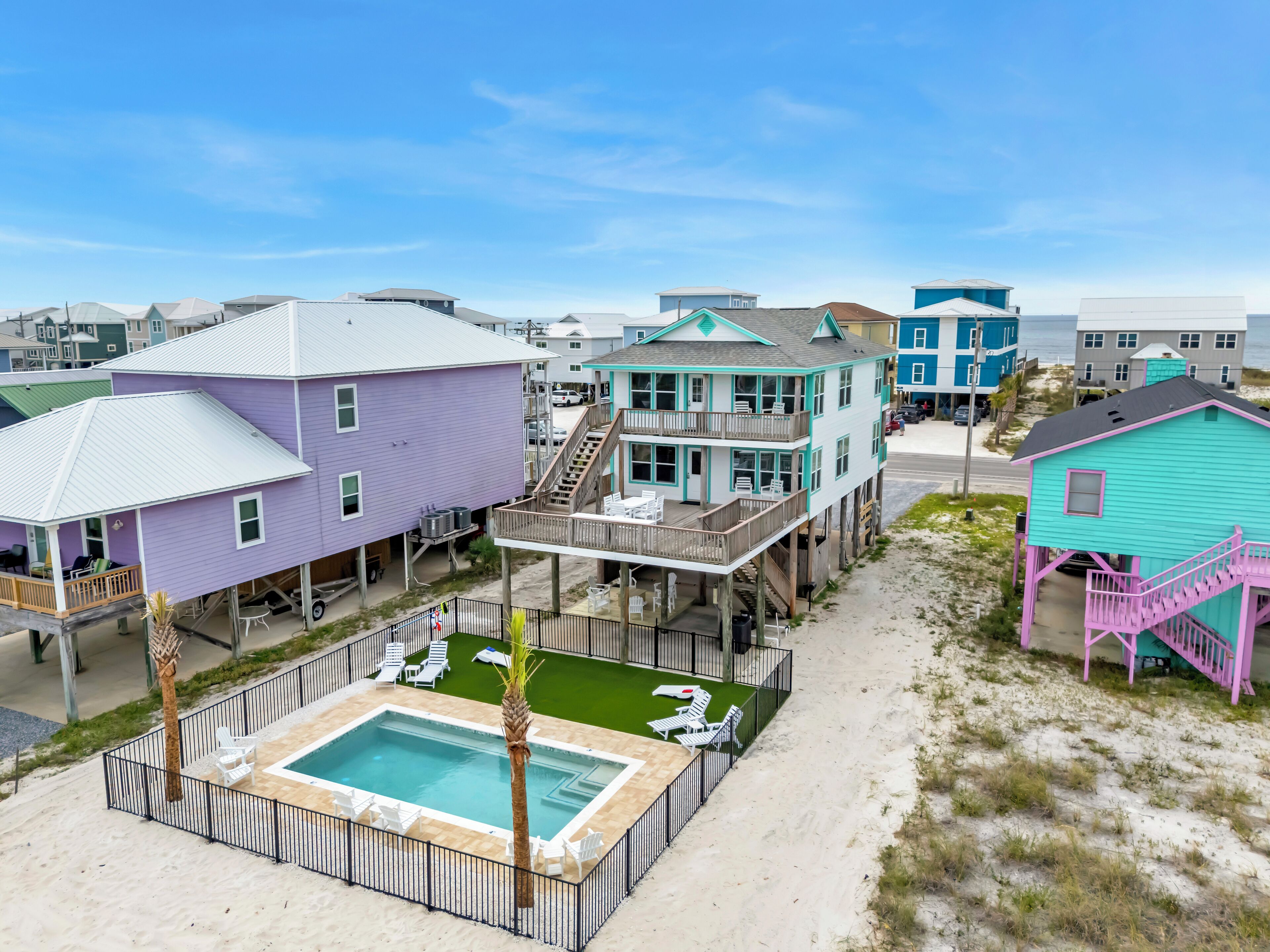 A beachfront property with a swimming pool, multiple buildings, and a sandy beach.