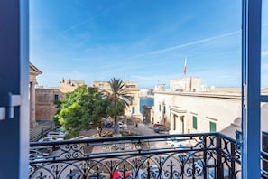 Ein Balkon mit Blick auf eine Stadtlandschaft, darunter Gebäude und eine Flagge.