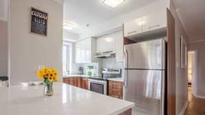 Eine moderne Küche mit Edelstahlgeräten, Holzschränken und einer weißen Arbeitsplatte.