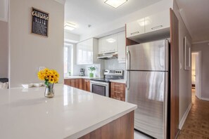 Eine moderne Küche mit Edelstahlgeräten, Holzschränken und einer weißen Arbeitsplatte.