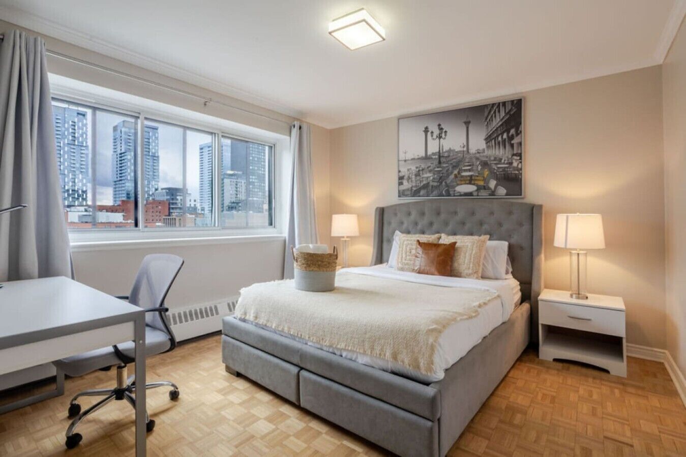 A modern hotel room with a large bed, a desk, and a view of the cityscape.