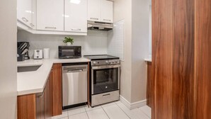 Une cuisine compacte avec des meubles blancs, un four à micro-ondes, un grille-pain, un lave-vaisselle et une cuisinière.