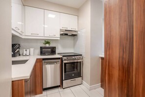 A compact kitchen with white cabinets, a microwave, a toaster, a dishwasher, and a stove. - Upscale Apartment in Montréal (Montreal)