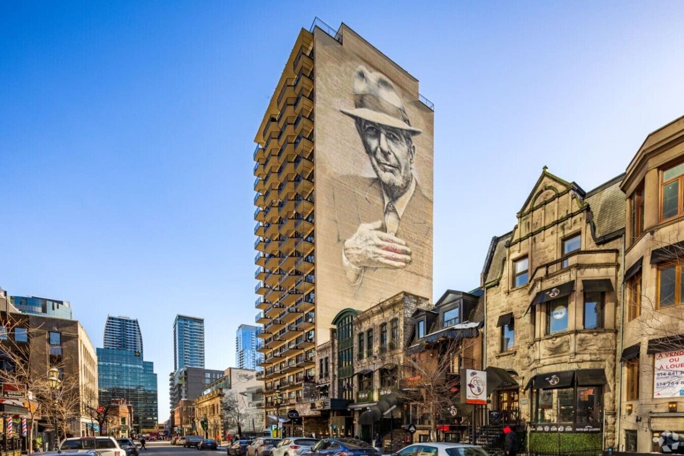 A tall building with a mural of a man holding a wine glass, surrounded by historic buildings and modern skyscrapers.