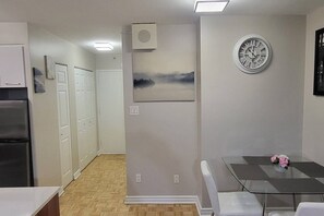A kitchen with a refrigerator, a dining table with chairs, a clock, and a painting on the wall. - Sophisticated Montréal Retreat (Montreal)