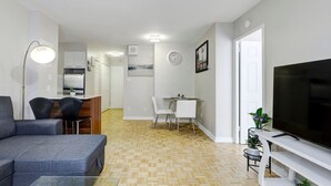 En modern lägenhet med vardagsrum, matplats, kök och en TV.