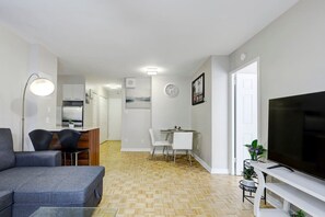 Eine moderne Wohnung mit Wohnzimmer, Essbereich, Küche und Fernseher.