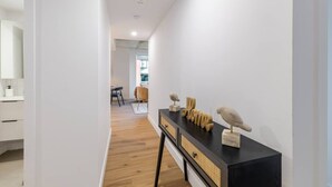 Een modern interieur met een houten vloer, een zwarte console tafel met decoratieve objecten, en uitzicht op een eetgedeelte.