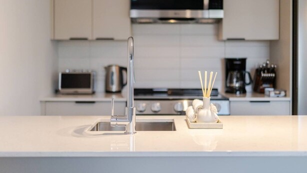 Een moderne keuken met een spoelbak van roestvrij staal, een magnetron en een koffiezetapparaat.