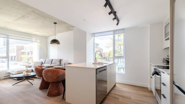 A modern kitchen with a central island, a dining area with a sofa and chairs, and large windows providing natural light. - The Velvet Loft Montréal (Montreal)