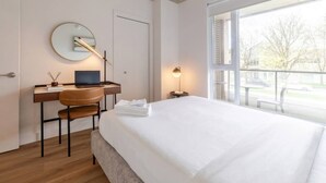 Ein modernes Hotelzimmer mit Bett, Schreibtisch, Stuhl und einem großen Fenster.