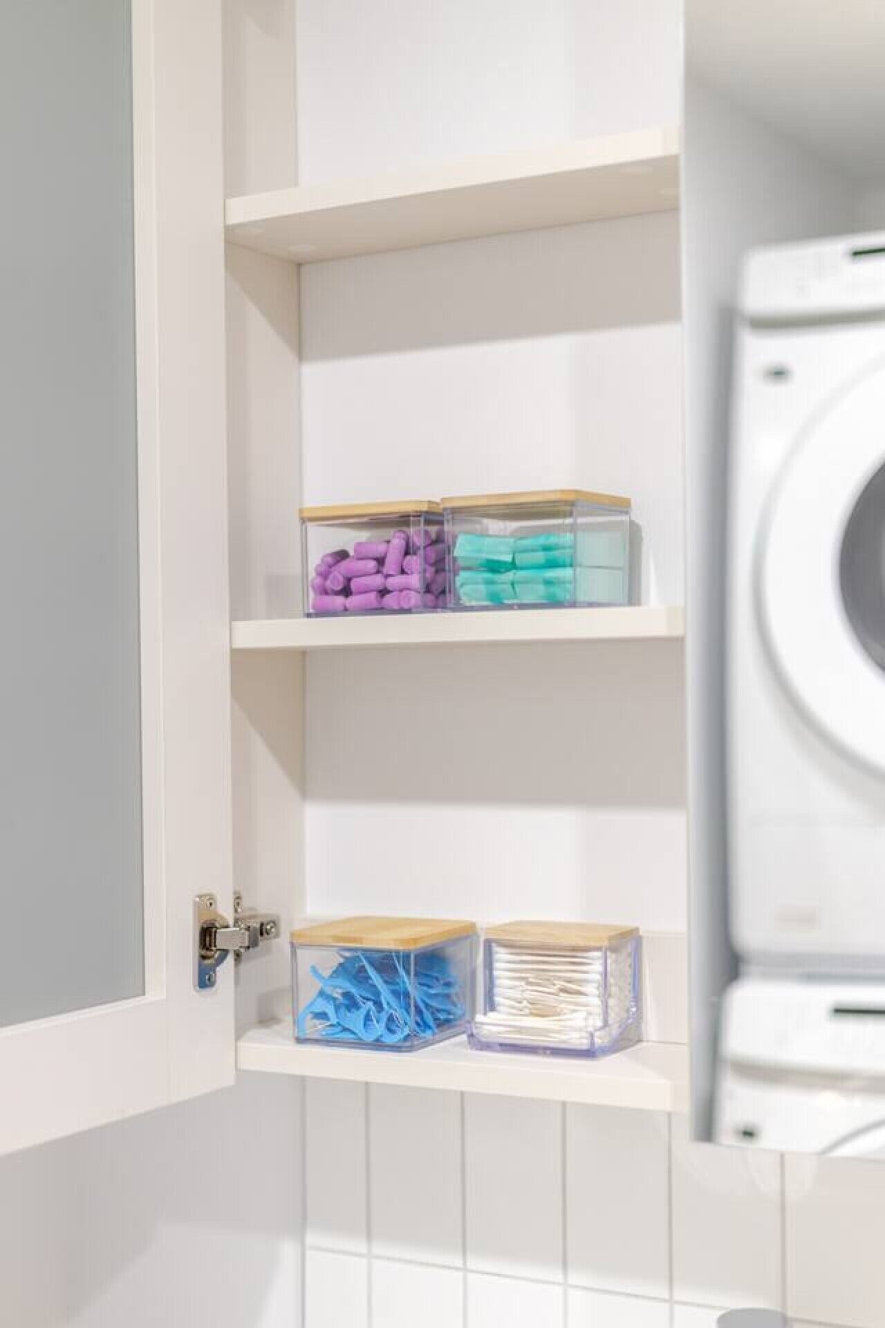 A laundry room with a washing machine, shelves with storage bins, and a door with a lock.