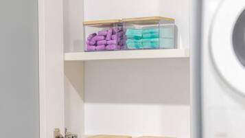 A laundry room with a washing machine, shelves with storage bins, and a door with a lock.
