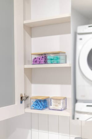 Un cuarto de lavado con lavadora, repisas con contenedores de almacenamiento y una puerta con cerradura.
