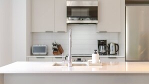 Eine moderne Küche mit Spüle aus Edelstahl, einer Mikrowelle und einem Kühlschrank.