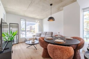 A modern living room with a round dining table, grey sofa, and a large window. - The Velvet Loft Montréal (Montreal)