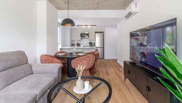 Ein modernes Wohnzimmer mit einer Couch, einem Couchtisch und einem Fernseher.