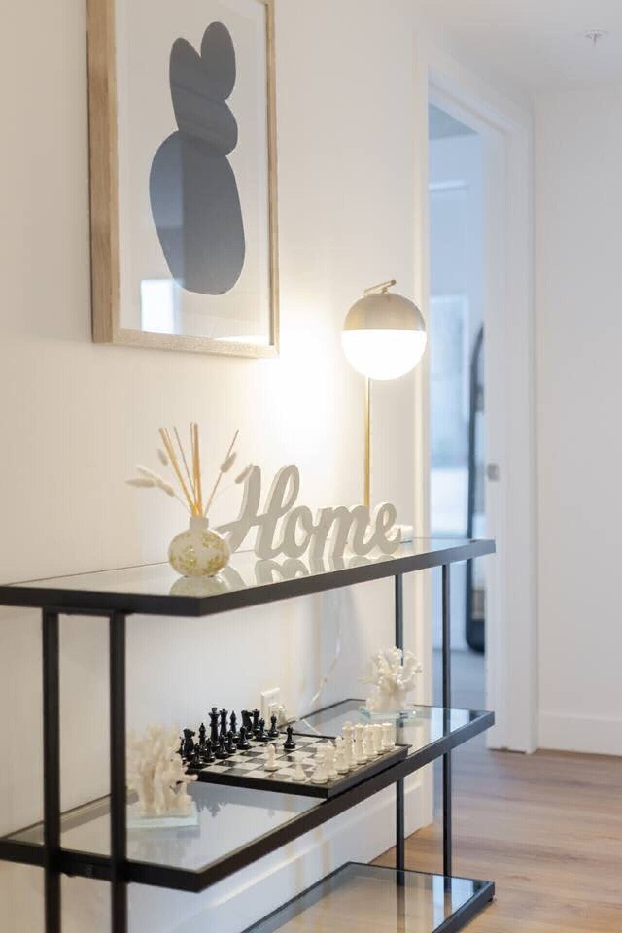 A modern living room with a glass coffee table, a chess set, and a decorative vase.