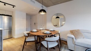 A modern kitchen with a dining table set for four, a sofa, and a round mirror on the wall. - CityGlow Montréal w/ Free Parking (Montreal)