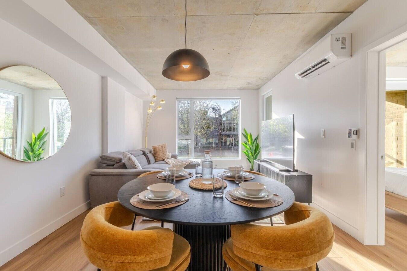 A modern dining area with a round table, four chairs, and a pendant light.