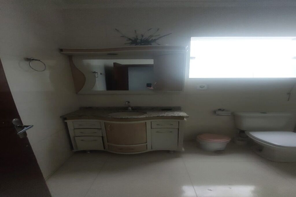A small bathroom with a sink, mirror, toilet, and a window.