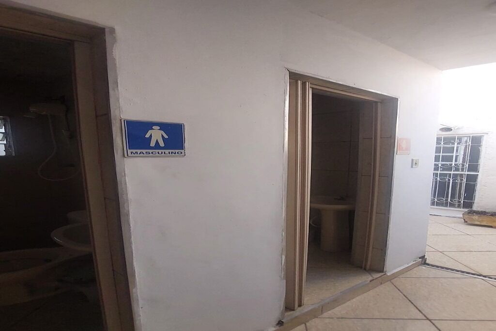 A men's restroom with a blue sign, a door, and a tiled floor.