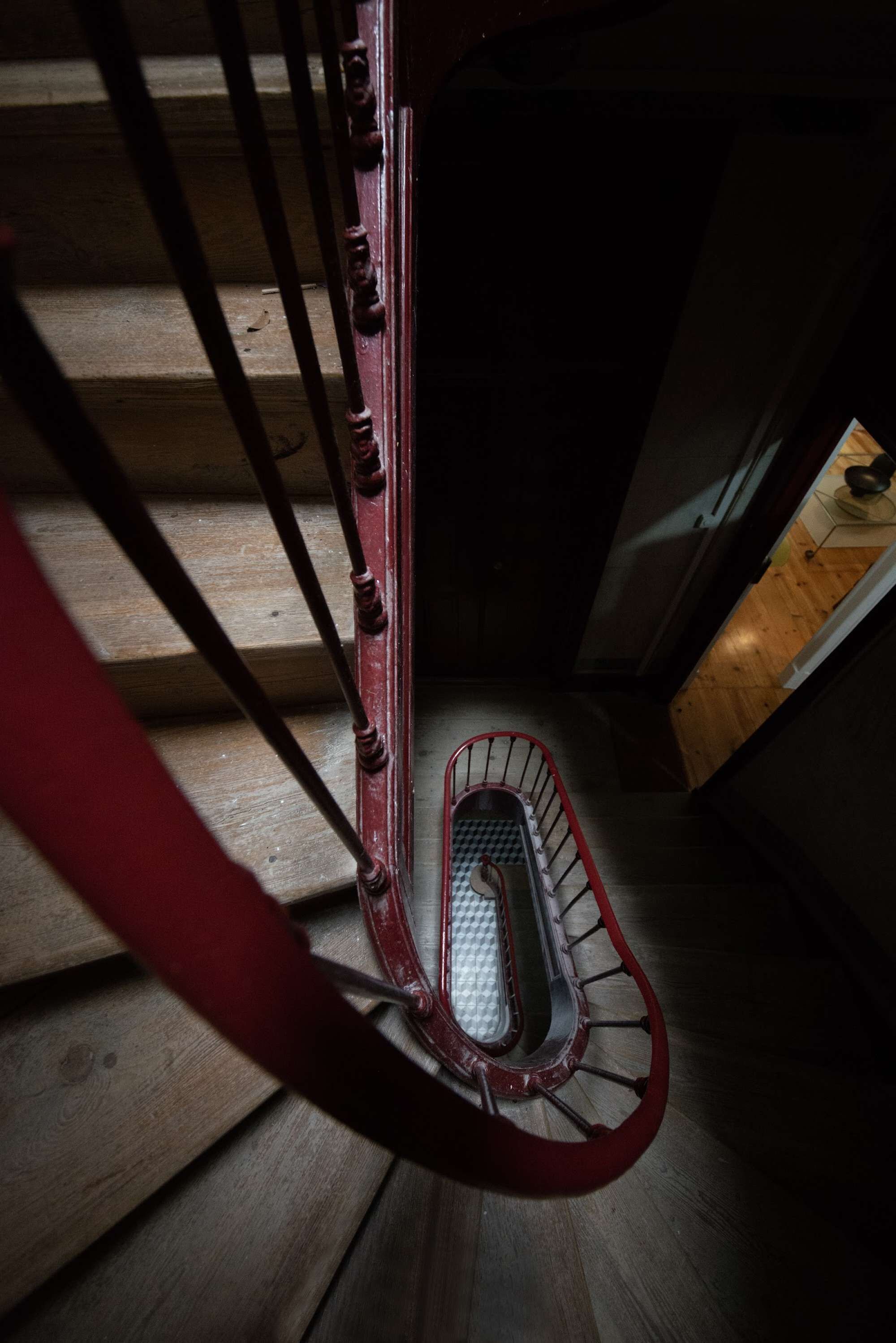 A wooden staircase with a red handrail and a metal safety railing.