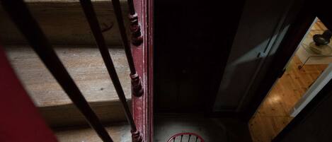 A wooden staircase with a red handrail and a metal safety railing.