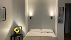 Une chambre à coucher avec un lit, des lampes de chevet, une petite table avec une lampe et un tableau encadré au mur.