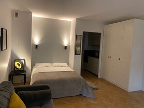 Ein Schlafzimmer mit einem Bett, Nachttischlampen, einem Kleiderschrank und einem kleinen Tisch mit einer Lampe.