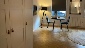 Une pièce comprenant une table à manger, des chaises, une lampe, une plante en pot, une fenêtre, un radiateur et un miroir.