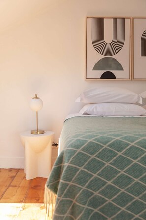 Ein Schlafzimmer mit einem Bett, einer Nachttischlampe und zwei an der Wand befestigten Kunstwerken.