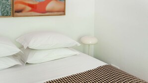 A bed with white bedding, a patterned throw, and a wall-mounted lamp. - Cheese&Wine™ | Amoreiras Garden 3 (Lisbon)