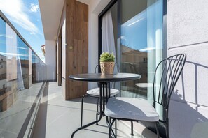 A balcony with a glass door, a round table with a plant, and two chairs. - LXR Indico 2-Bedroom Apartment by the Sea (Fuengirola)