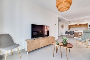 A modern living room with a TV, sofa, and dining area. - LXR Indico 2-Bedroom Apartment by the Sea (Fuengirola)