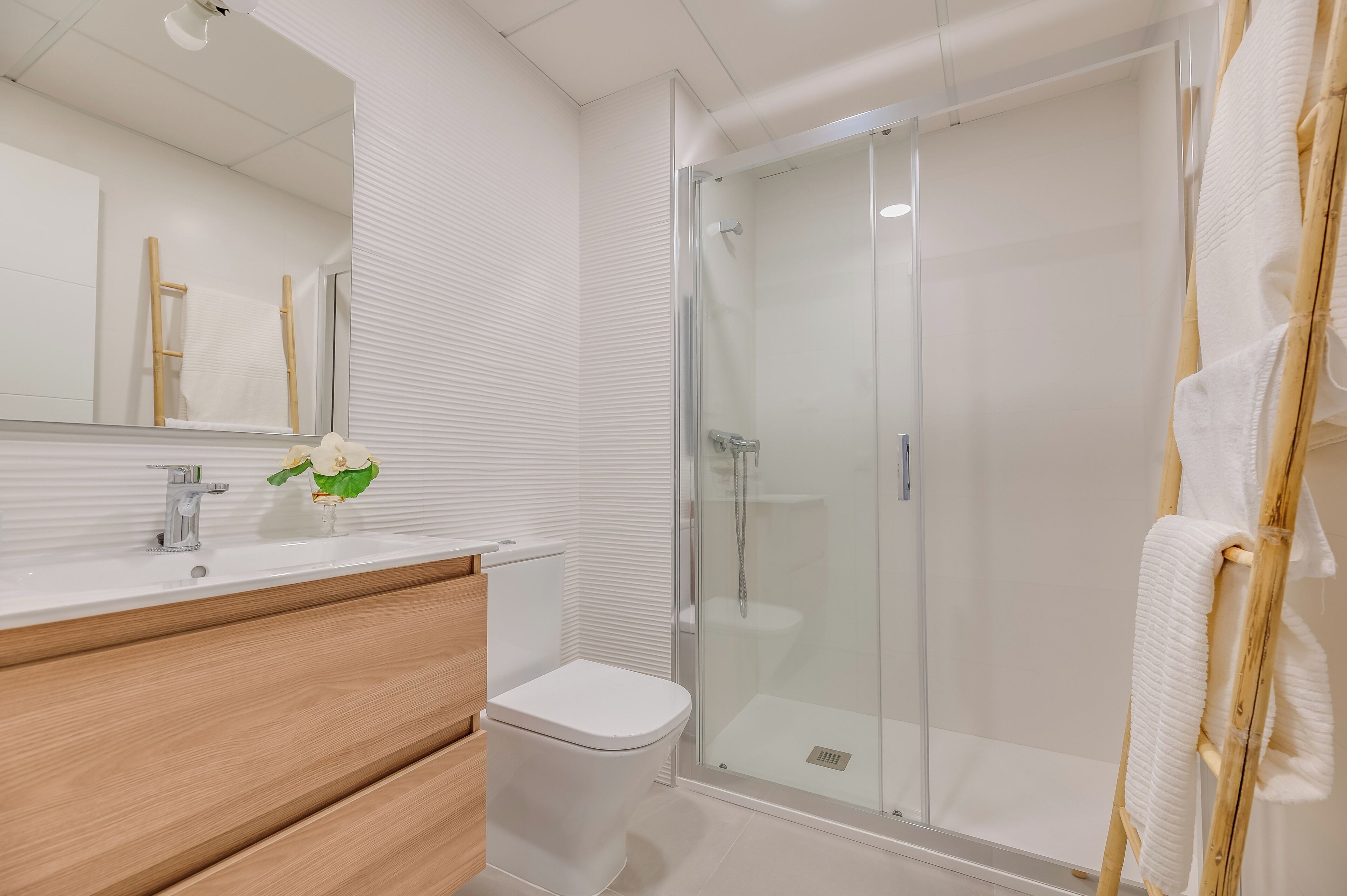 A modern bathroom with a toilet, sink, and glass-enclosed shower.