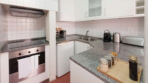 Eine Küche mit weißen Schränken, einem Edelstahlbackofen, einer Mikrowelle, einem Toaster und einer Kaffeemaschine.