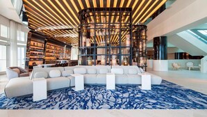 A modern interior with a sectional sofa, a patterned carpet, and a ceiling with wooden slats.