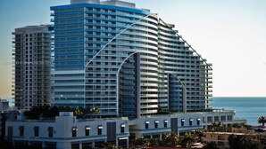 A modern high-rise hotel with multiple balconies, large windows, and a curved architectural design.